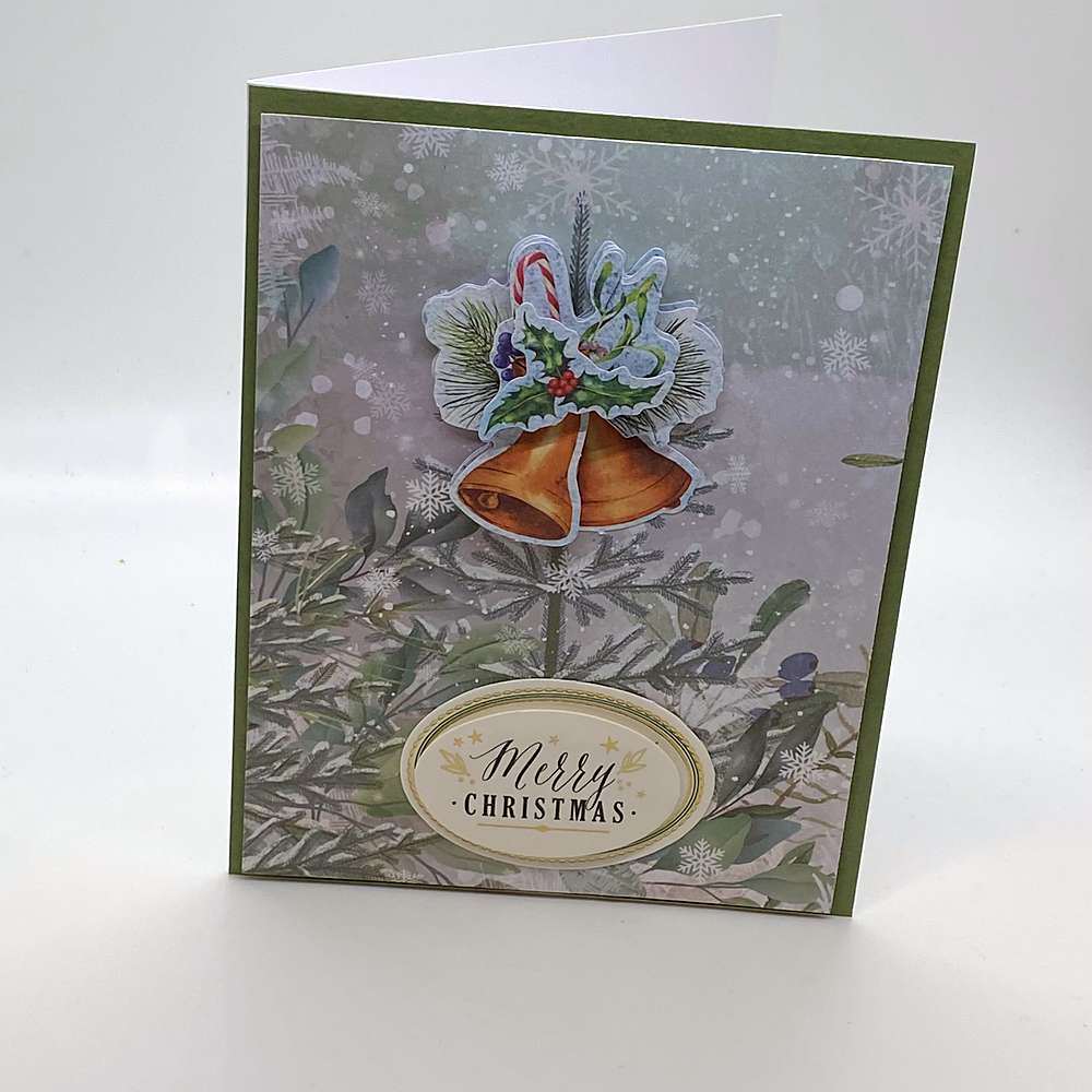 3D bells Christmas card on a sage green mat with raised orange bells, holly and candy canes over snowy pine branch paper, and an oval label at the bottom. Text reads: "Merry Christmas" - Grammy's Grams Handmade Greeting Cards